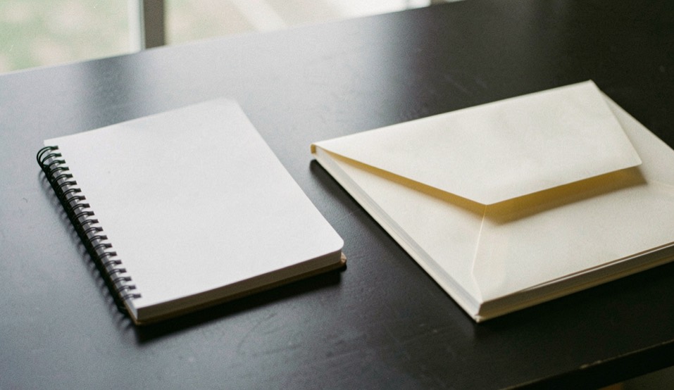 Documentary photograph of a blank disclosure card beside a notebook and a closed envelope on a dark desk, no readable text, calm daylight. Distinct lead composition for this editorial entry.